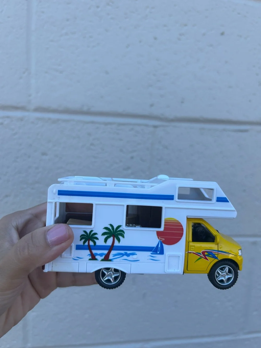 Bright yellow and white toy camper van with colorful beach graphics collectible